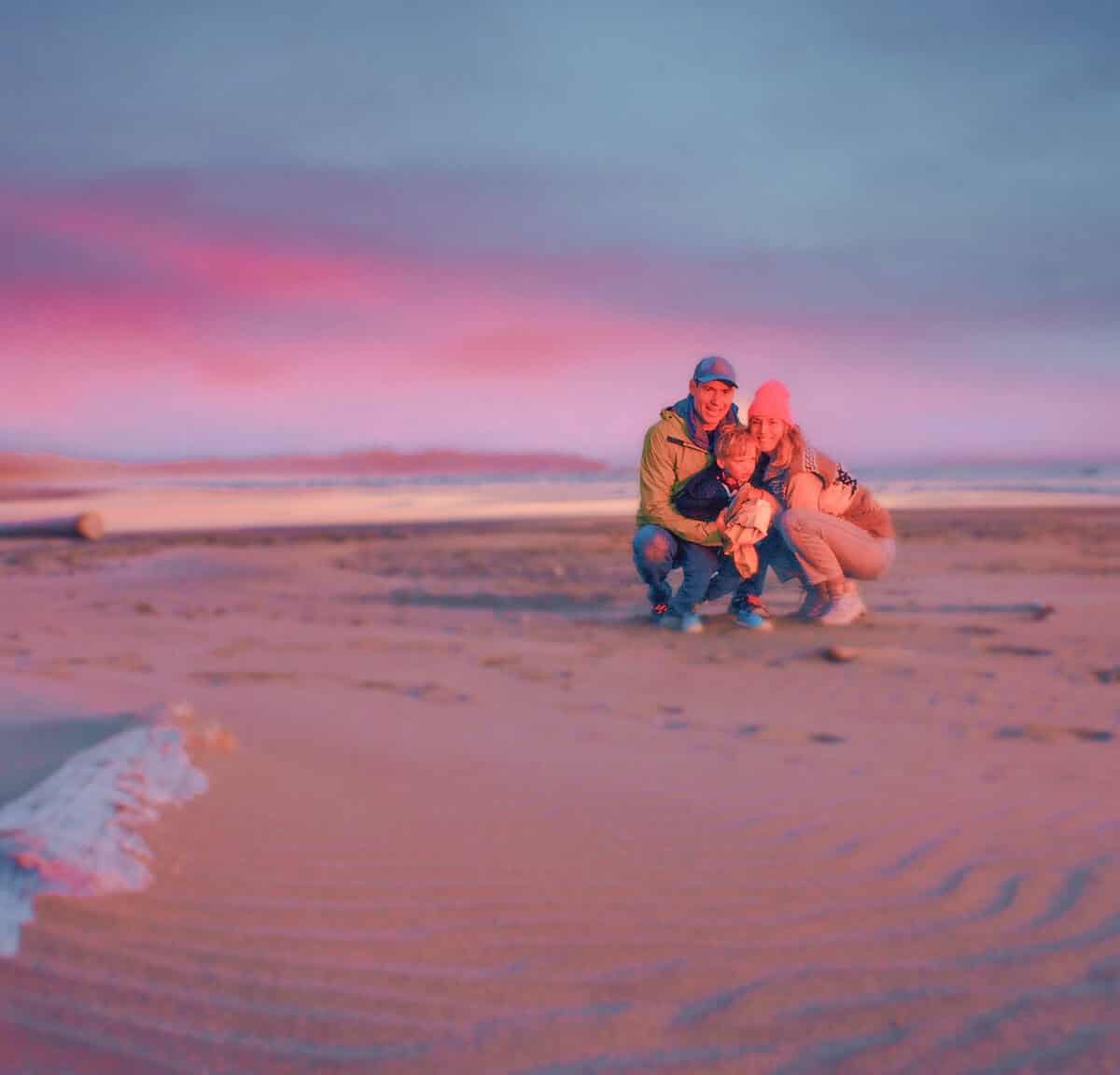 A family with a young child plays at a beach in Tofino.
