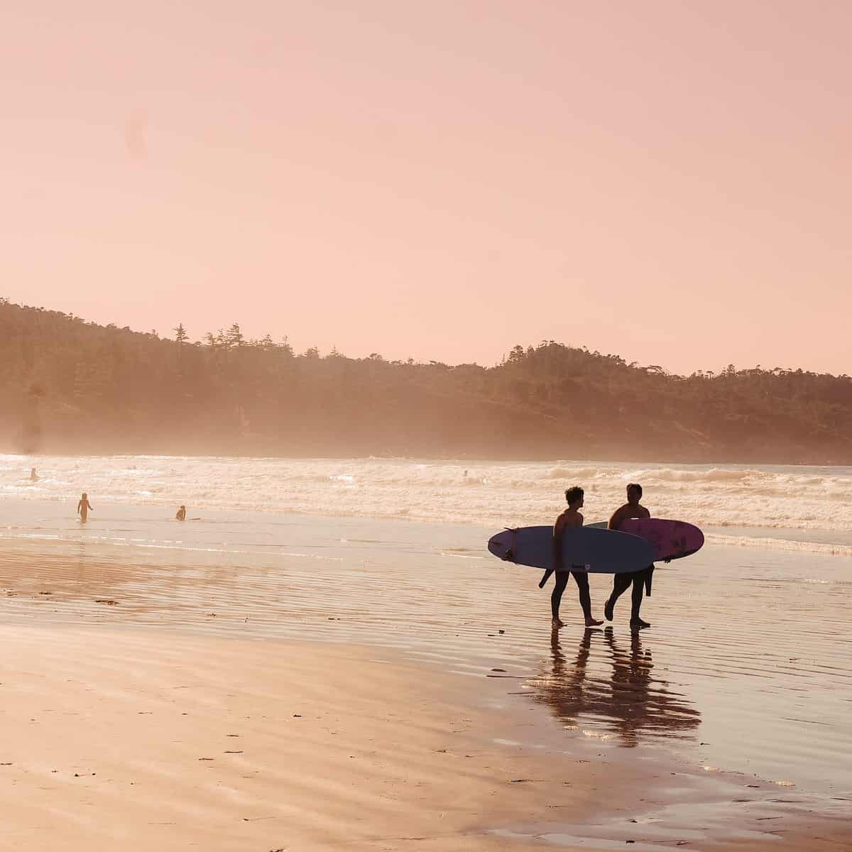 Surfers walking along the beach at Cox Bay Tofino